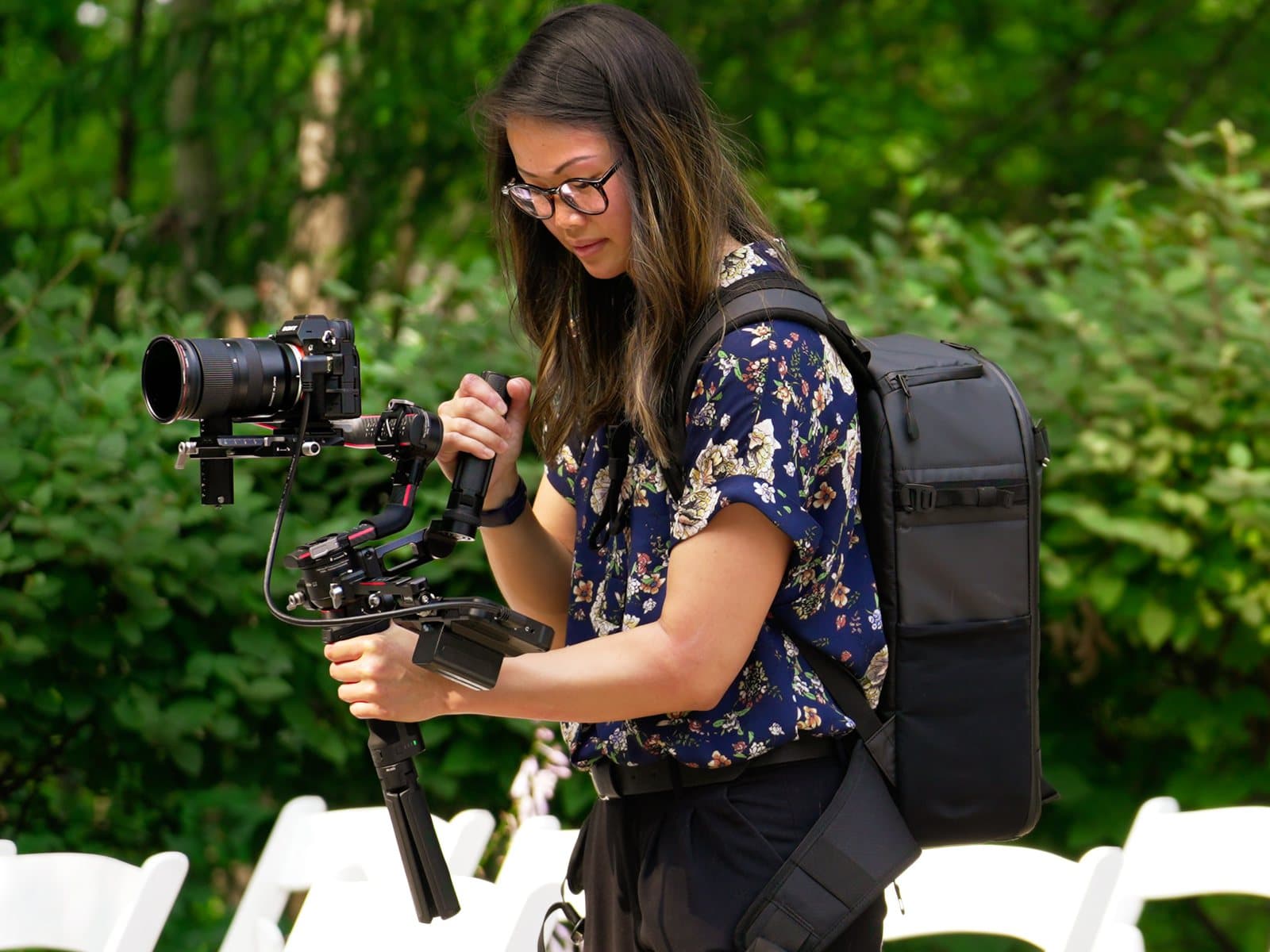 A Skytona filmmaker with a gimbal rig at an outdoor ceremony site.